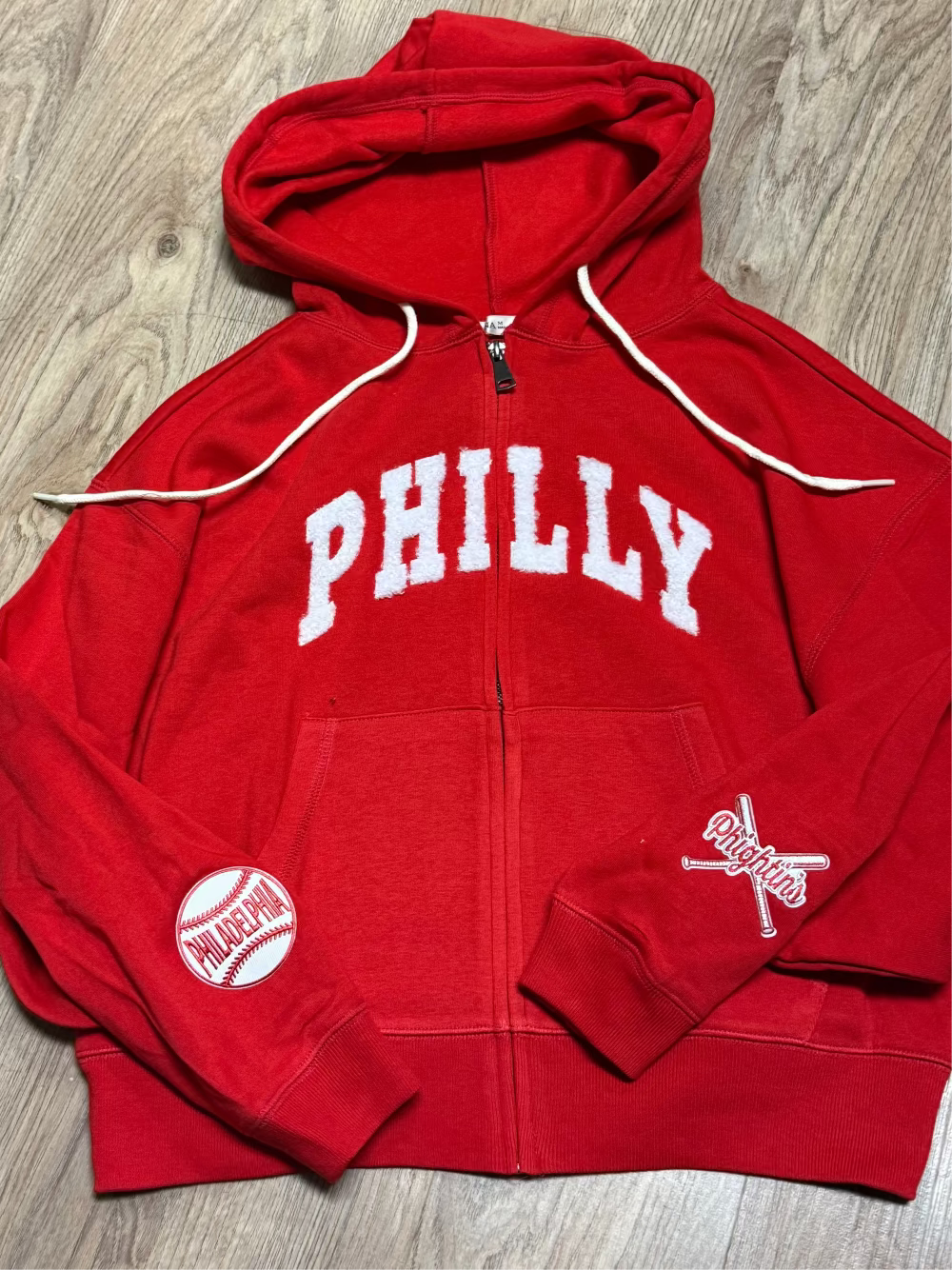 Red hoodie with 'PHILLY' text on a wooden floor